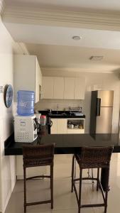 a kitchen with a counter with two chairs and a microwave at Recanto Ville House in Porto Seguro