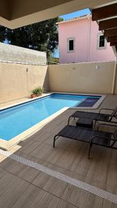 a swimming pool with two chairs next to a house at Recanto Ville House in Porto Seguro