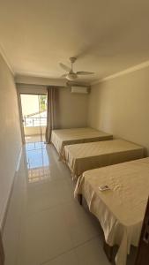 a room with three beds and a window at Recanto Ville House in Porto Seguro