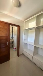 a room with white shelves and a wooden door at Recanto Ville House in Porto Seguro