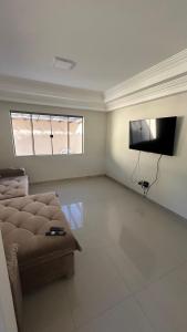 a living room with a couch and a flat screen tv at Recanto Ville House in Porto Seguro