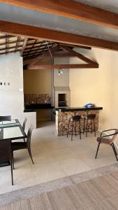 a living room with tables and chairs and a counter at Recanto Ville House in Porto Seguro