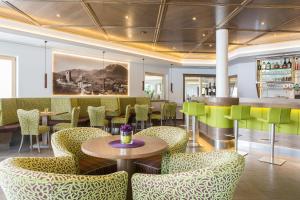 a restaurant with chairs and tables and a bar at Astor Hotel in Schenna