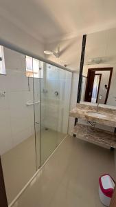a bathroom with a glass shower and a mirror at Recanto Ville House in Porto Seguro