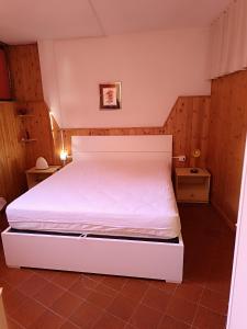 1 dormitorio con 1 cama blanca en una habitación en Le Marmotte - Appartamento, en Abetone