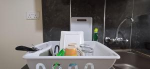 a white container with utensils in it next to a sink at B&S Studio apartment, Voi Town in Voi
