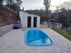 a blue swimming pool in a yard with a house at Casa de campo com piscina a 2 min de cunha in Cunha