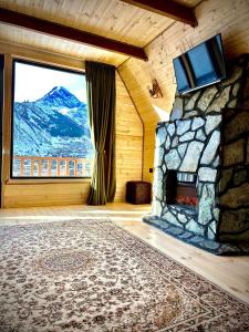 a room with a stone fireplace with a mountain view at Hillside Kazbegi in Kazbegi