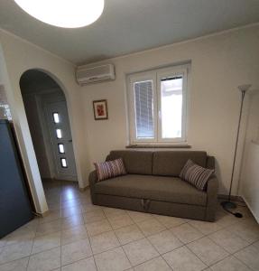 ein Wohnzimmer mit einem Sofa und einem Fenster in der Unterkunft Apartma Laura in Ankaran