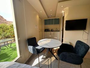 een kleine kamer met een tafel en stoelen en een televisie bij Naseem Country House in Al Ula