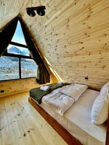 a bed in a wooden room with a large window at Hillside Kazbegi in Stepantsminda