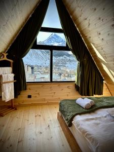 a bedroom with a bed and a large window at Hillside Kazbegi in Stepantsminda