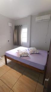 um quarto com uma cama com duas almofadas e uma janela em Ap térreo a 50 metros do mar em Balneário Gaivotas