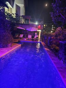 una piscina notturna con luci viola di Apartamentos Casa da Pedra a Ubatuba