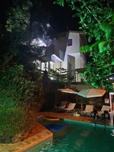 una piscina con sillas y sombrillas junto a un edificio en Apartamentos Casa da Pedra en Ubatuba