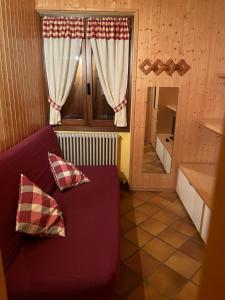 sala de estar con sofá púrpura y ventana en Appartamento Lidia piano terra, en Santa Maria Maggiore