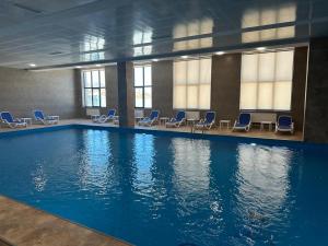 a large swimming pool with blue chairs in a building at Tsaghkadzor Alvina complex in Tsaghkadzor
