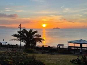 einen Sonnenuntergang über dem Meer mit einer Palme in der Unterkunft Littlesea Haven fleetview in Weymouth