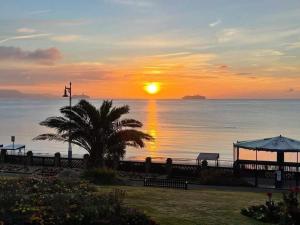 a sunset over the ocean with a palm tree at Littlesea Haven fleetview in Weymouth