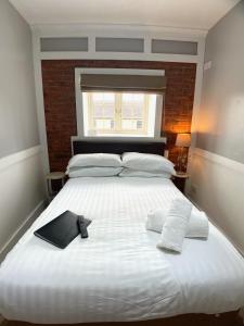 a large white bed with a remote control on it at The Lawns Hotel in Derby