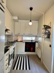 a kitchen with white cabinets and a black and white rug at Central 2 Br in Tampere