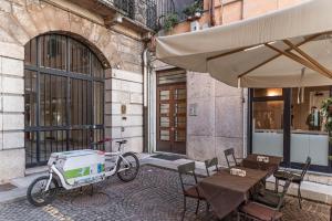We Home - Romeo&Giulietta Luxury Retreat في فيرونا: دراجة متوقفة بجانب مبنى فيه مظلة