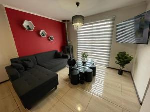 ein Wohnzimmer mit einem schwarzen Sofa und einer roten Wand in der Unterkunft Amplia Casa en Condominio in La Serena