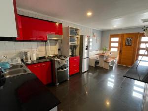 una cocina con armarios rojos y electrodomésticos de acero inoxidable en Amplia Casa en Condominio, en La Serena