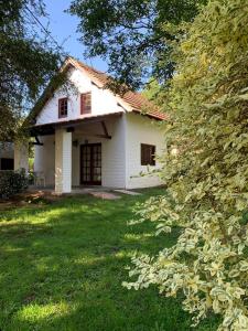 una casa bianca con un prato e alberi di Loma Dorada Cabañas a Villa General Belgrano Altre 7 foto