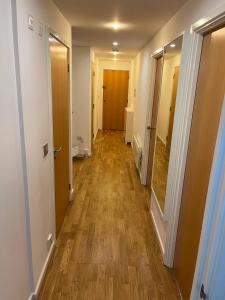 un pasillo de un apartamento con suelo y puertas de madera en Ensuite Room in Royal Victoria Excel O2 Arena London en Londres