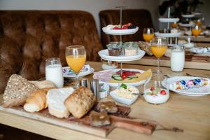 una mesa cubierta con mucha comida y vasos de zumo de naranja en B&B de Cley, en Noordwijk