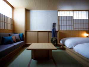 a woman in a room with two beds and a table at 黒梅屋 Kurumiya in Kanazawa