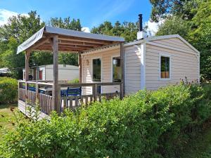 WittelteTiny house的白色小屋设有木制甲板和凉亭