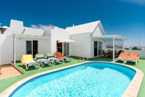 a villa with a swimming pool in front of a house at Villa Reyes in Tías