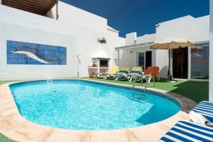a pool with chairs and an umbrella next to a house at Villa Reyes in Tías