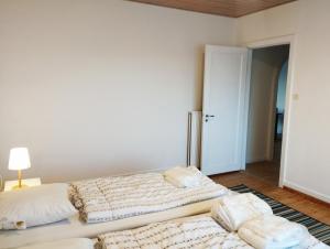 (Id022) Strandby Kirkevej 270 1 th في إيسبيرغ: سريرين في غرفة بيضاء مع مصباح