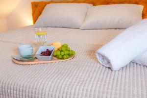 a tray of fruit and a drink on a bed at Dusznickie Apartamenty Julia in Duszniki Zdrój