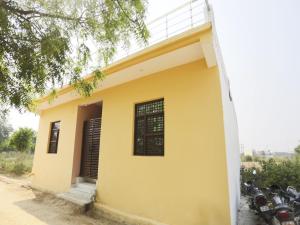 ein gelbes Haus mit davor geparkt in der Unterkunft OYO Hotel Pari in Greater Noida