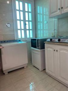 une cuisine avec des placards blancs et un four micro-ondes sur un comptoir dans l'établissement Falcon heaven, à Ville du 6 Octobre