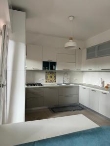 una cucina bianca con armadi bianchi e lavandino di Nomadi Sedentari - Matera a Matera