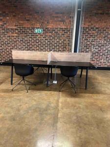 a wooden table and two chairs in front of a brick wall at Premium Cozy Apartment (0% loadshedding) in Sandton