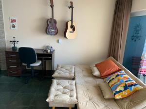 a living room with a couch and a desk and guitar at Studio do Wander in Amparo