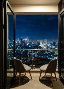 een balkon met 2 stoelen en uitzicht op de stad bij Luxury Apartment with Saigon River View - Zenity in Ho Chi Minh-stad