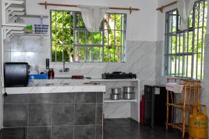 een keuken met een wastafel en 2 ramen bij Garden house 2 in Ukunda