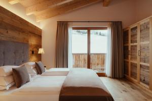 a bedroom with two beds and a large window at Villa Flora Mountain Lodges in San Cassiano