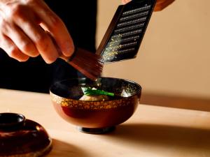 a person is stirring a bowl with a whisk at 井波古香里庵 別邸 瑞雲 in Nanto