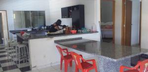 a woman in a kitchen with a counter and chairs at Chácara Bela Suíça in Itatiba