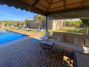 a living room with a couch and a pool at Villa famille Bilal Agafay in Marrakesh
