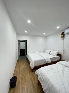 two beds in a room with white walls and wooden floors at Agarwood in Hanoi