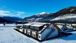 uma casa na neve com montanhas ao fundo em DARO living Top 7 em Sankt Margarethen im Lungau